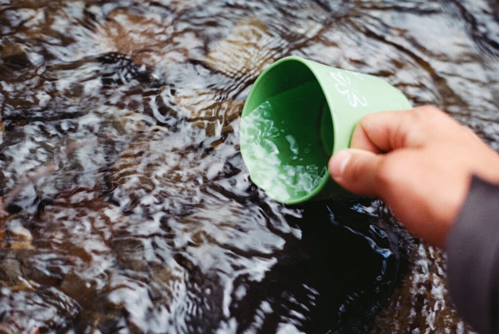 person scooping water using green cup